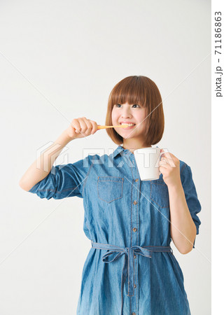 カップを手に持ち歯を磨く若い女性 カップを手に持ち歯を磨く若い女性 71186863