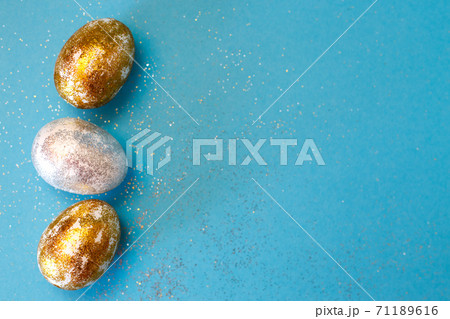 Gold and silver Easter eggs on a blue background. Easter concept. Happy Easter. Copy space 71189616
