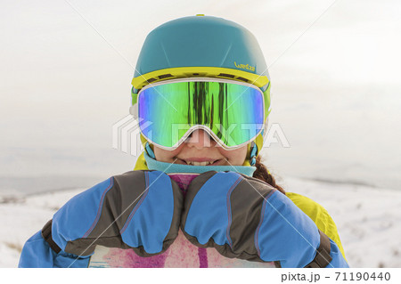 Close-up girl with a snowboard posing on a panorama of the mountains. Focus on mittens Close-up girl with a snowboard posing on a panorama of the mountains. Focus on mittens 71190440