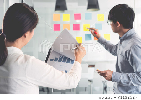 Business manager showing idea for her team and stick many memo paper on glass window to success working in business meeting  creative office, planning and management concept. 71192527