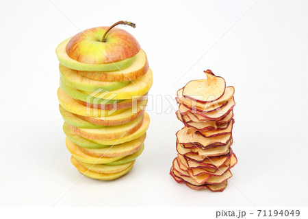 pieces of fresh and dried apples stacked in a pyramid on a white background 71194049