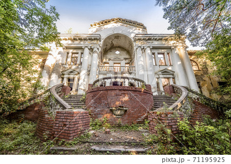 Abandoned dilapidated building in old park. Sweeping staircases, columns and a balustrade 71195925