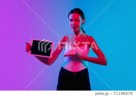 Young caucasian woman's portrait on gradient blue-purple studio background in neon light Young caucasian woman's portrait on gradient blue-purple studio background in neon light 71196879
