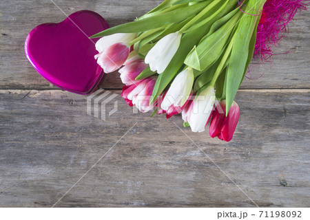 Beautiful greeting card for Valentine's day. Bouquet of fresh tulips and gift box shape heart on old non paint wooden background. Space for text, flat lay 71198092