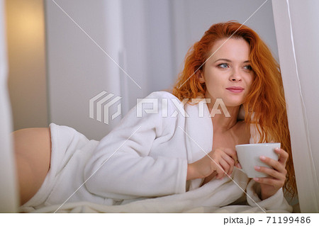 Beautiful young woman with cup of coffee at home 71199486