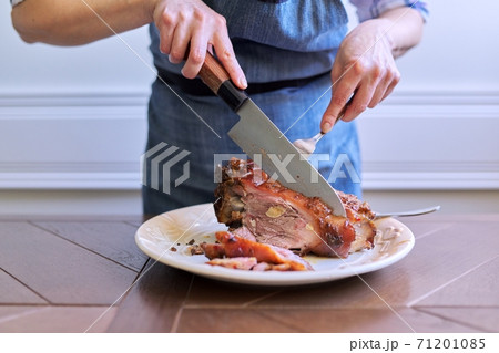 Female hands cutting freshly cooked hot meat on plate Female hands cutting freshly cooked hot meat on plate 71201085