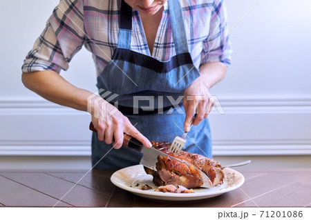 Female hands cutting freshly cooked hot meat on plate 71201086