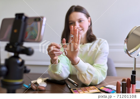 Teenage girl, beauty blogger filming video for channel blog, showing eyelash curler 71201108