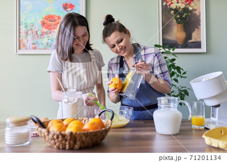Mother and teenage daughter cook pancakes together at home in kitchen 71201134