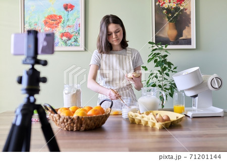 Girl teenager food blogger cooking orange pancakes at home in kitchen 71201144
