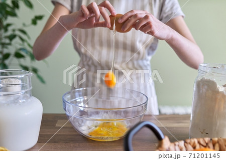 Close-up of breaking an egg in bowl, preparing dough for pancakes 71201145