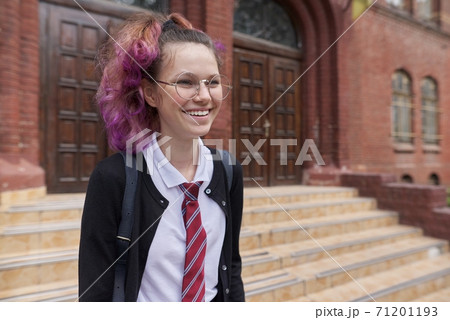 Female student teenager in uniform with backpack, building school background 71201193