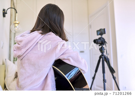 Teenage girl playing an acoustic guitar, recording video for channel, blog 71201266