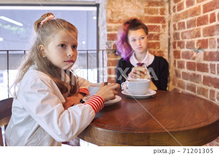 Children, two sisters sitting together in cafe at table Children, two sisters sitting together in cafe at table 71201305