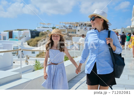 Mother walking with daughter child in famous tourist village Oia Santorini 71202081
