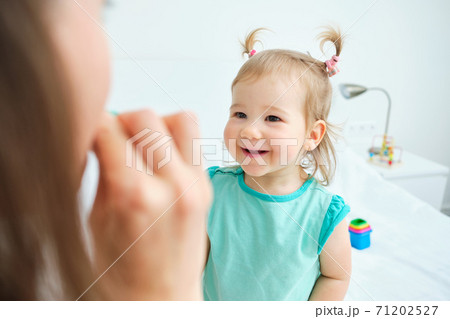Caucasian toddler smiles at mom and looks at her Caucasian toddler smiles at mom and looks at her 71202527