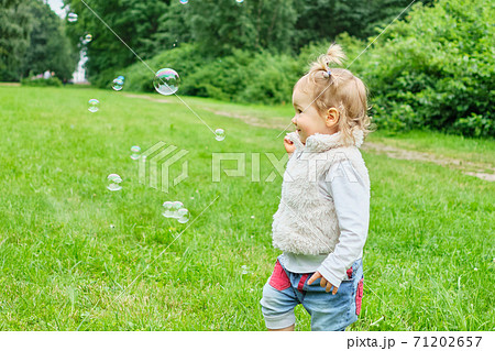 Caucasian toddler running for soap bubbles in summer time Caucasian toddler running for soap bubbles in summer time 71202657