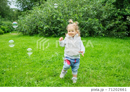 Caucasian kid blowing soap bubbles in the park 71202661