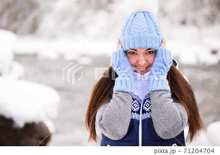 Beautiful young woman smiling and playing with snow in winter season Beautiful young woman smiling and playing with snow in winter season 71204704