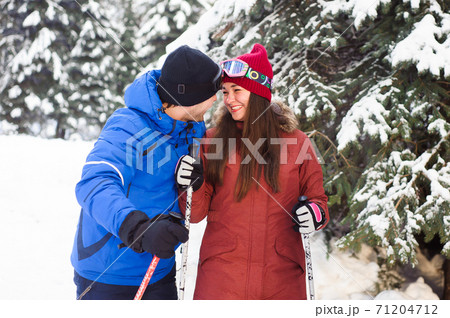 happy married couple skiing at a ski resort in the forest 71204712