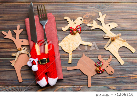 New year set of fork and knife on napkin. Top view of christmas decorations and reindeer on wooden background. Close up of holiday family dinner concept 71206216