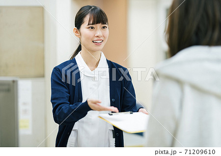 病院の窓口で案内する医療事務スタッフ 71209610