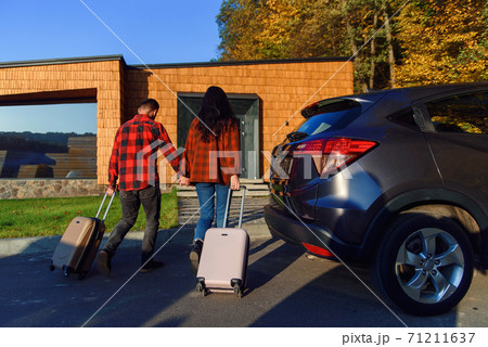 Lovely couple moving to new house goes with suitcases to enter new home. Moving time. Lovely couple moving to new house goes with suitcases to enter new home. Moving time. 71211637