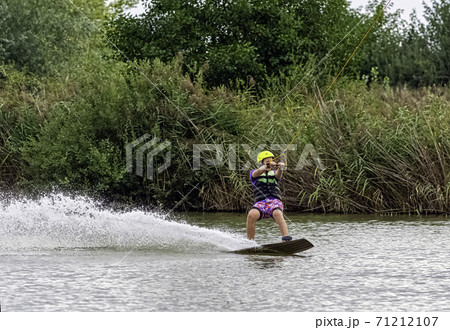 Teenager wakeboarding on a lake - Brwinow, Masovia, Poland Teenager wakeboarding on a lake - Brwinow, Masovia, Poland 71212107