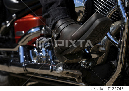 Biker riding a motorcycle. Bottom view of the legs in leather cowboy boots 71227624