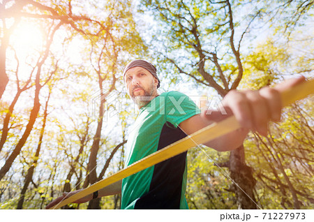 Portrait of a bearded man in age stands near a taut slackline in an autumn forest 71227973