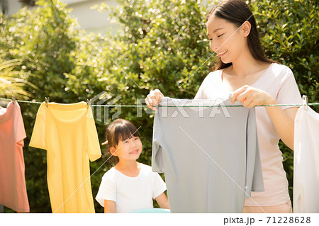 お母さんの洗濯物を干す家事を手伝う小さい女の子 お母さんの洗濯物を干す家事を手伝う小さい女の子 71228628