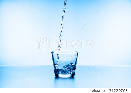 water splashing from glass isolated on blue background water splashing from glass isolated on blue background 71229763