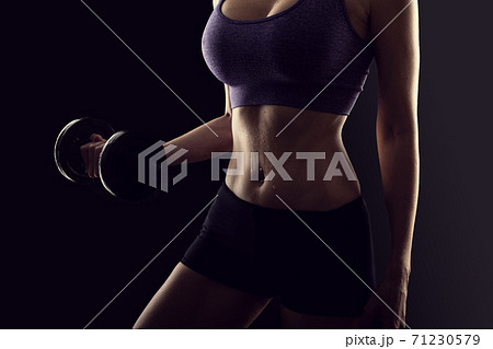 Slim athletic woman Holding dumbbell in the hand on black Slim athletic woman Holding dumbbell in the hand on black 71230579