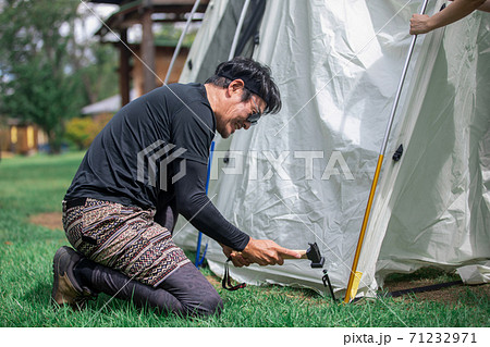 キャンプ場でハンマーを使ってテントを組み立てるアジア人男性 71232971