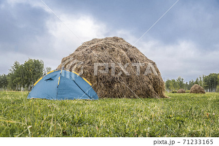 Tent on the field with mowed grass next to a haystack in autumn Tent on the field with mowed grass next to a haystack in autumn 71233165