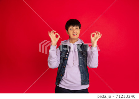 Senior woman isolated on red background. Tech and joyful elderly lifestyle concept 71233240