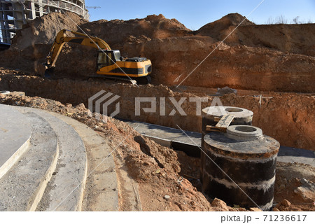Excavator on earthwork during the laying of pipes of heating system building at construction site.  71236617
