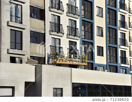Suspended construction cradle on the background facade of the building. Suspended construction cradle on the background facade of the building. 71236620