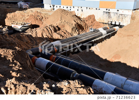 Laying heating pipes in a trench at construction site. Install underground storm systems  71236623