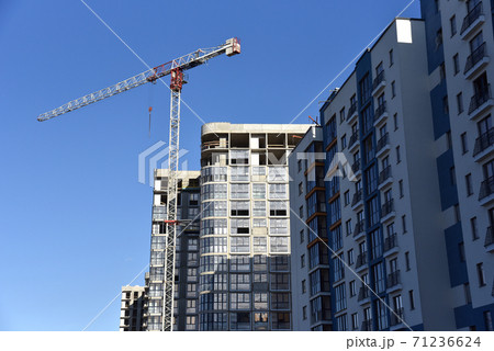 Tower crane working at construction site on blue sky background with white clouds.  71236624