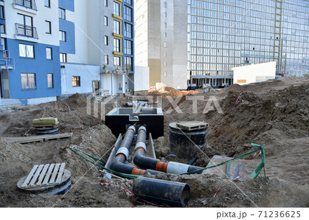 Laying heating pipes in a trench at construction site. Install underground storm systems  71236625