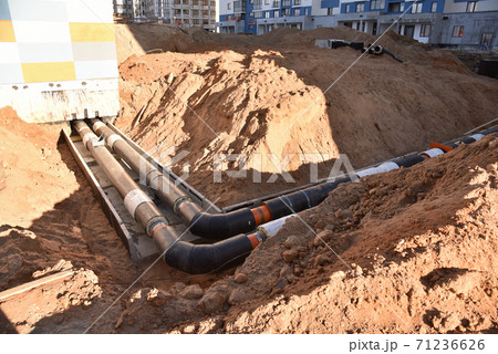 Laying heating pipes in a trench at construction site.  71236626