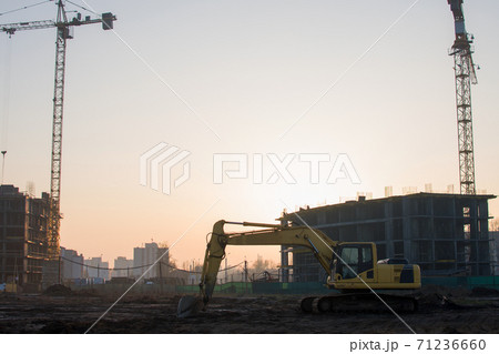 Excavator at construction site on a background of a construction cranes and building. Excavator at construction site on a background of a construction cranes and building. 71236660