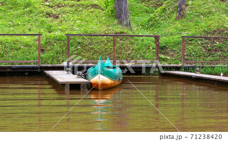 A boat on a lake is parked on a jetty A boat on a lake is parked on a jetty 71238420