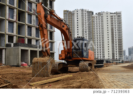 Bucked excavator digs ground at a construction site for installing concrete storm pipes. Bucked excavator digs ground at a construction site for installing concrete storm pipes. 71239363