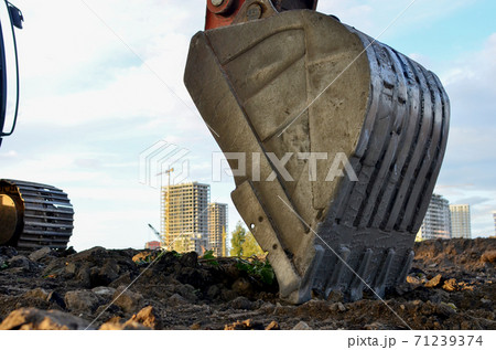 Large metal iron ladle. Excavator bucket for digging a pit and pipeline ditch at a construction site Large metal iron ladle. Excavator bucket for digging a pit and pipeline ditch at a construction site 71239374