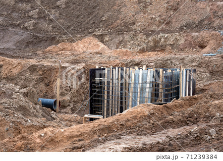 Connecting a trench drain to a valve pit and concrete manhole structure at construction site.  71239384