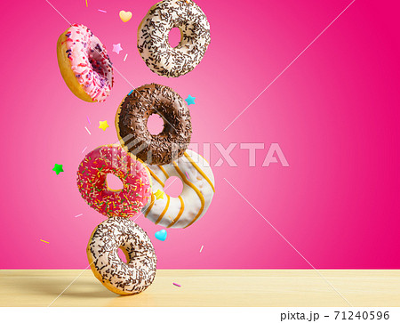 Flying donuts. Mix of multicolored sweet doughnuts with sprinkel on pink background falling on the table. Flying donuts. Mix of multicolored sweet doughnuts with sprinkel on pink background falling on the table. 71240596