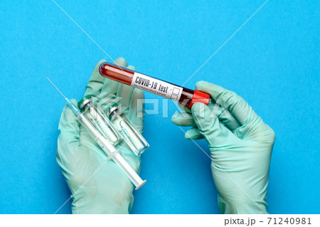 lab technician assistant or doctor wearing rubber or latex gloves holding an ampoule with medicine or vaccine and test tube with blood sample lab technician assistant or doctor wearing rubber or latex gloves holding an ampoule with medicine or vaccine and test tube with blood sample 71240981
