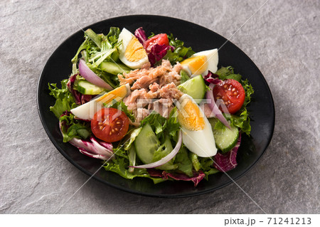 Salad with tuna, egg and vegetables on black plate and gray background Salad with tuna, egg and vegetables on black plate and gray background 71241213